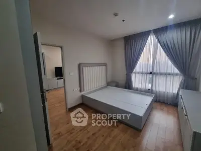 Spacious bedroom with wooden flooring and large window, perfect for natural light.