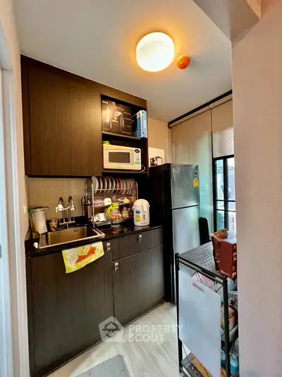 Compact kitchen with modern appliances and dark wood cabinets