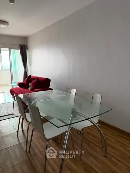 Modern living room with glass dining table and red sofa, featuring a bright and airy ambiance.