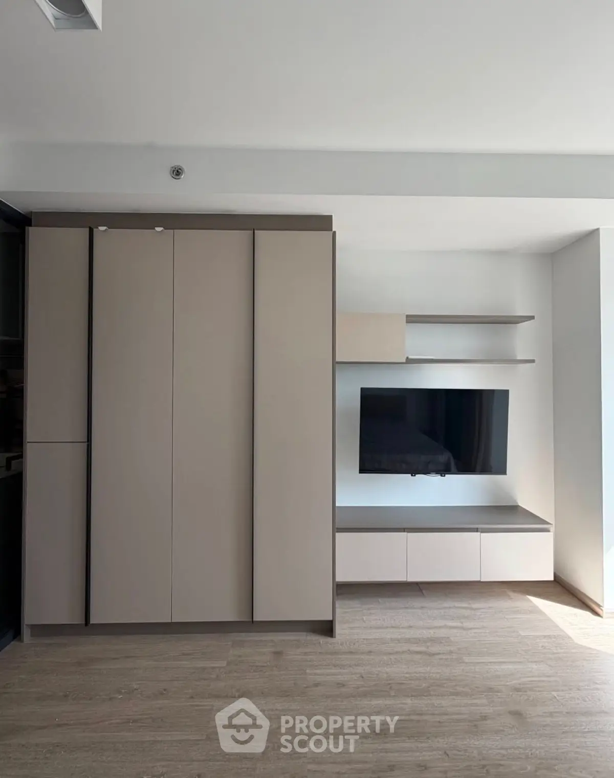 Modern living room with sleek built-in storage and TV unit, featuring minimalist design and ample natural light.