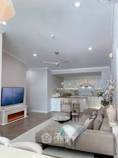 Modern living room with cozy seating and open kitchen layout, featuring elegant decor and ambient lighting.