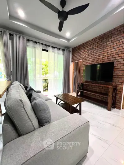 Modern living room with brick accent wall, large gray sofa, and sleek wooden furniture.