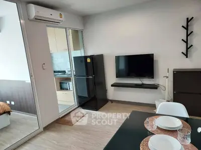 Modern living room with sleek TV setup and adjacent kitchen area in a stylish apartment.