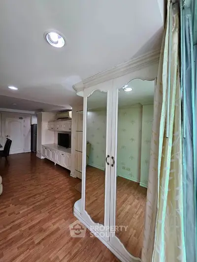 Spacious living room with elegant wooden flooring and mirrored wardrobe