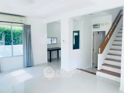 Bright and spacious living room with modern staircase and large window view.
