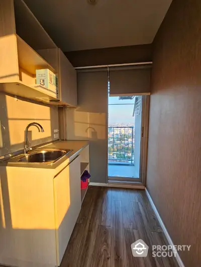 Sunlit compact kitchen with modern fittings, ample storage, and a charming balcony view, ideal for urban living in a cozy space.