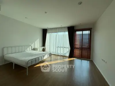 Spacious bedroom with large windows and wooden flooring, perfect for natural light lovers.