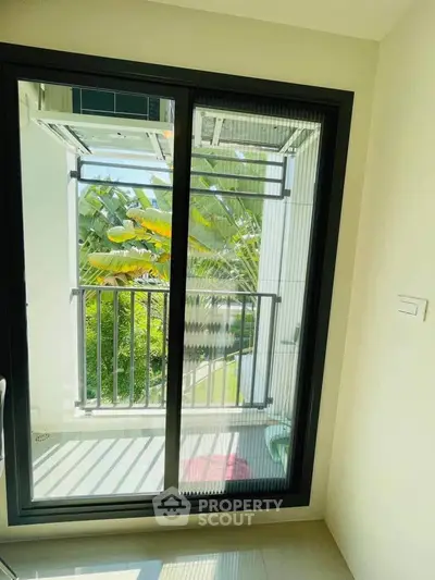 Bright balcony view with lush greenery through modern sliding glass door.