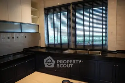 Modern kitchen with sleek black countertops and large windows with blinds