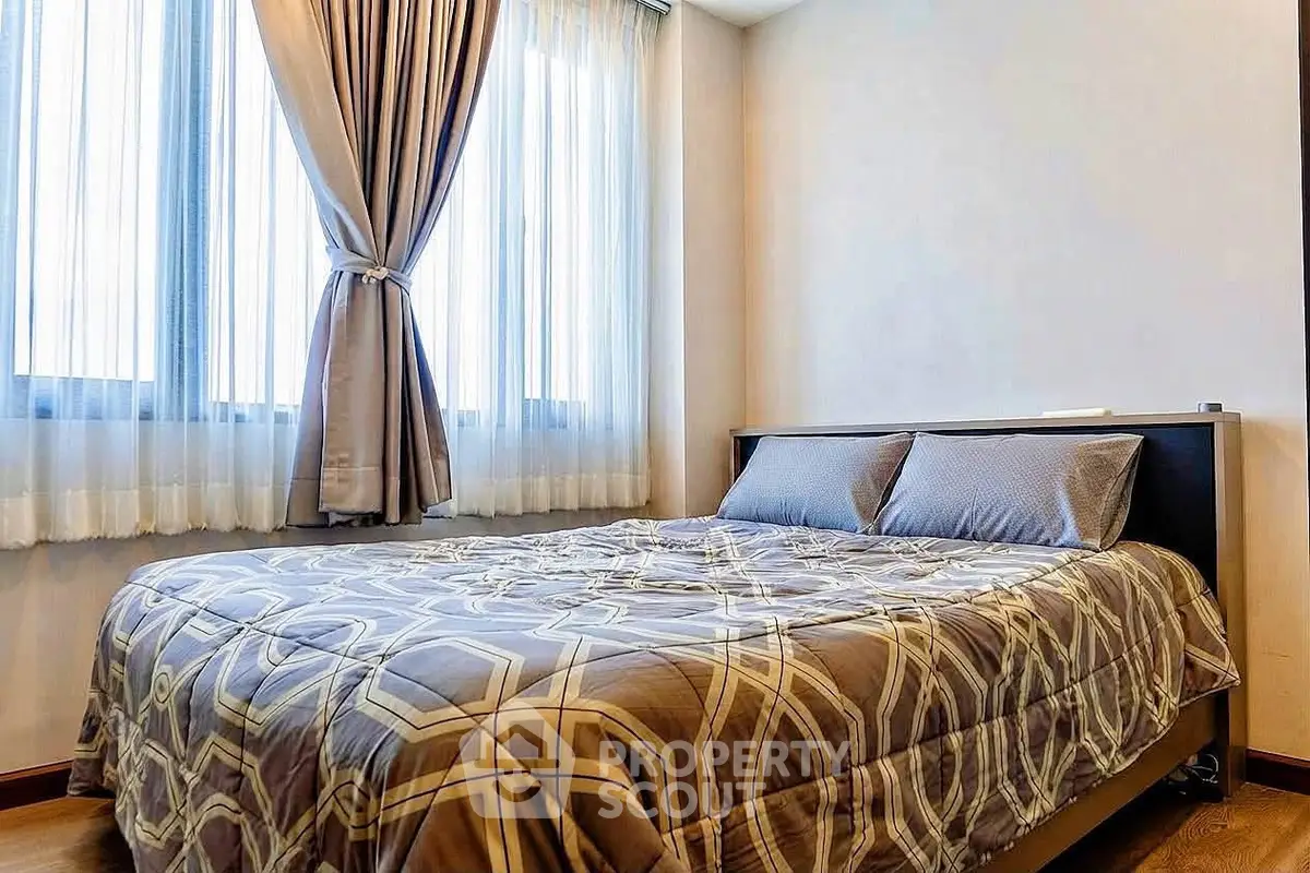 Cozy bedroom with elegant curtains and stylish bedding in a modern apartment.
