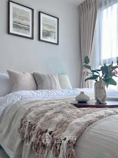 Elegant bedroom with cozy decor and natural light, featuring stylish bedding and framed art.