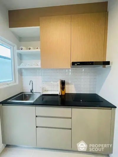 Modern kitchen with sleek cabinetry and built-in stove, featuring a minimalist design and ample natural light.