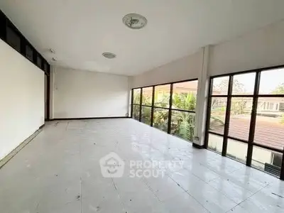 Spacious unfurnished room with large windows offering abundant natural light and garden views.