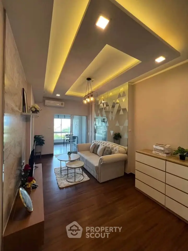 Modern living room with stylish ceiling lights and cozy seating area, leading to a bright balcony view.