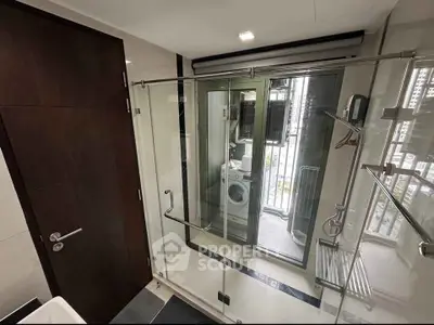 Modern bathroom with glass shower and view of laundry area with washing machine.