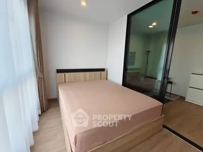 Modern bedroom with wooden flooring and large window for natural light