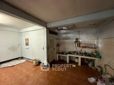 Spacious kitchen area with tiled floor and open shelving, ideal for renovation.
