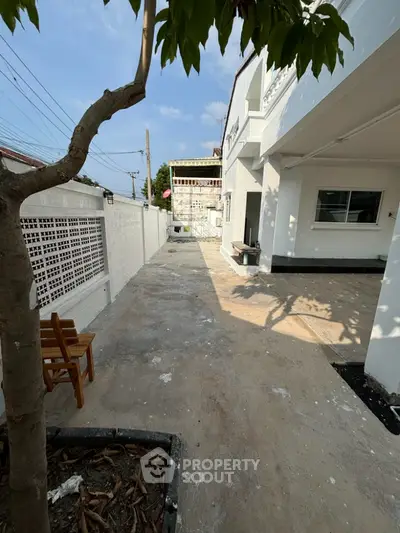Spacious outdoor area of modern home with paved walkway and tree shade