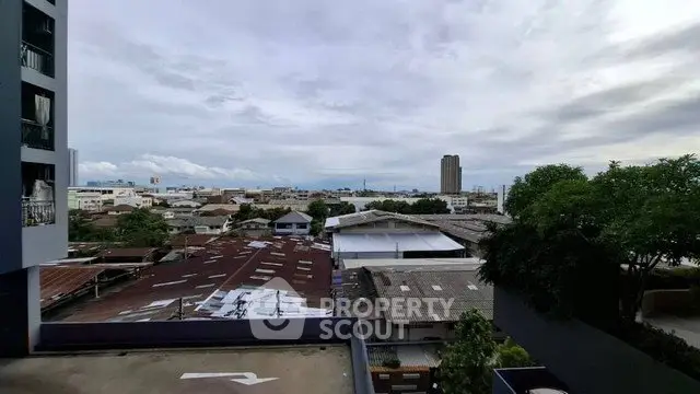 Stunning cityscape view from a high-rise building balcony, showcasing urban skyline and lush greenery.