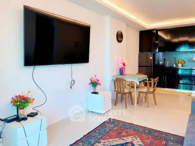 Modern living room with wall-mounted TV and sleek kitchen in open layout apartment.