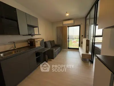 Modern living room with sleek kitchen and balcony view in a stylish apartment.