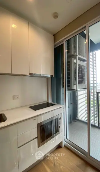 Modern kitchen with sleek white cabinets and balcony view