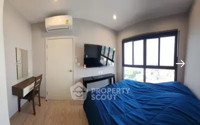Modern bedroom with large window, blue bedding, and wall-mounted TV