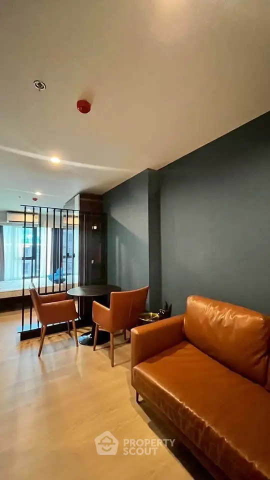 Modern living room with stylish leather sofa and dining area in open layout apartment.