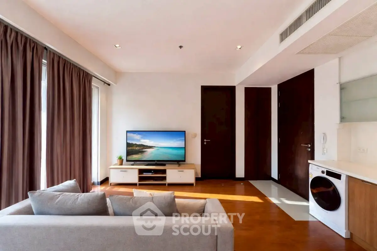 Modern living room with cozy sofa, flat-screen TV, and integrated washing machine in stylish apartment.