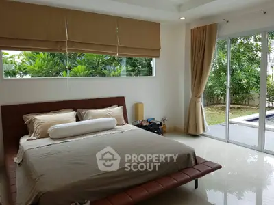 Luxurious bedroom with pool view and lush greenery, perfect for relaxation and comfort.