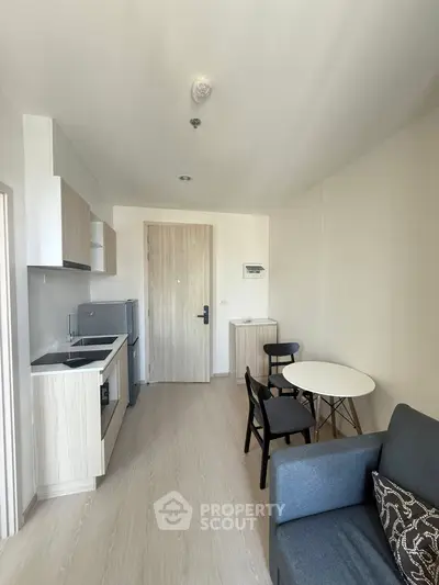 Modern compact living room with kitchenette and dining area in a cozy apartment.