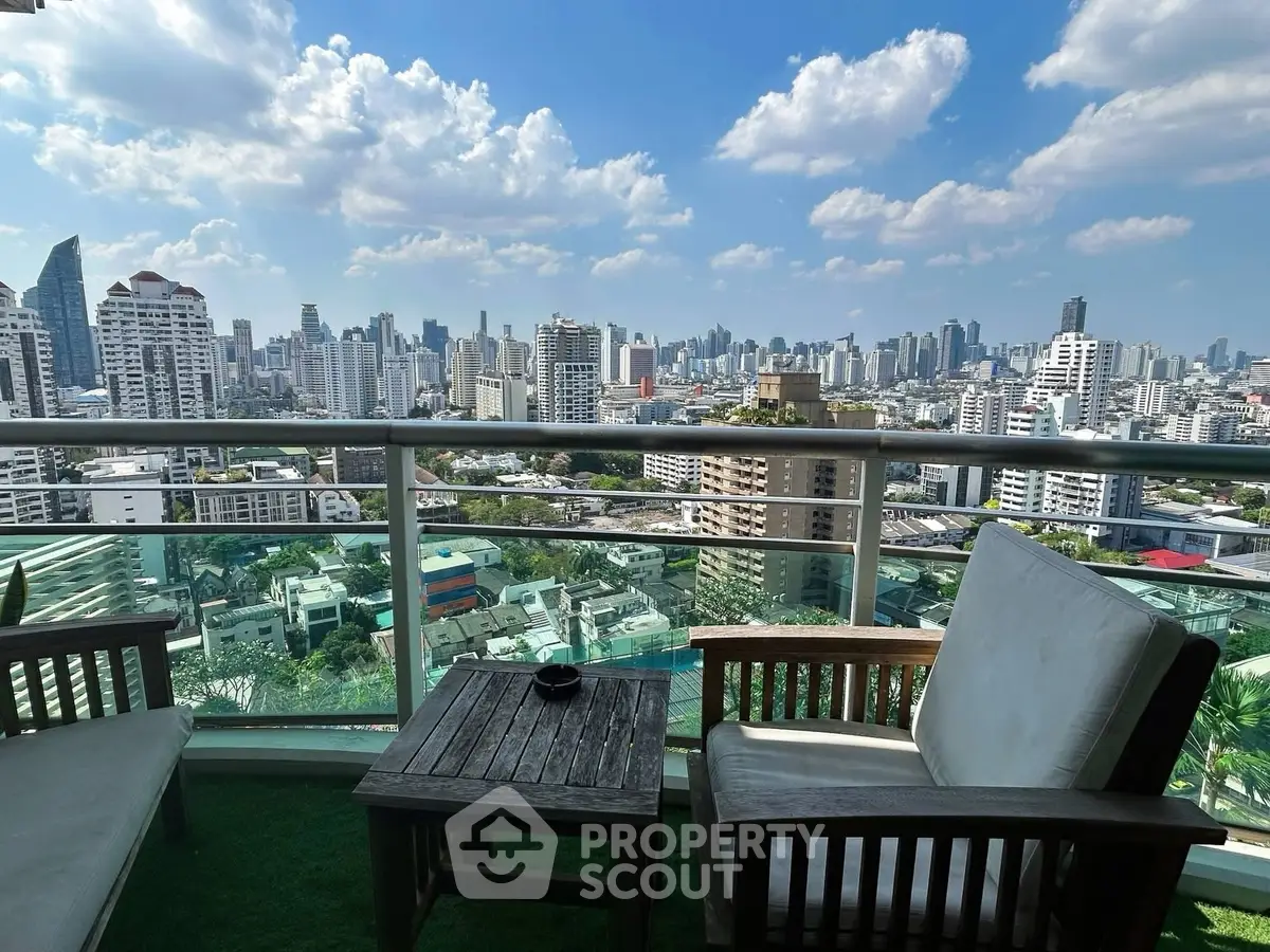 Stunning cityscape view from a high-rise balcony with cozy seating area, perfect for relaxation.