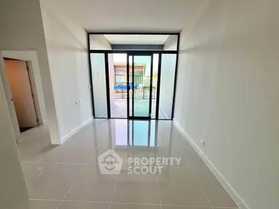 Spacious modern room with large glass doors leading to a balcony, perfect for natural light.
