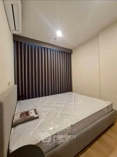 Modern bedroom with sleek design and large bed, featuring elegant curtains and air conditioning for comfort.