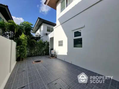 Spacious modern outdoor patio with tiled flooring and lush greenery