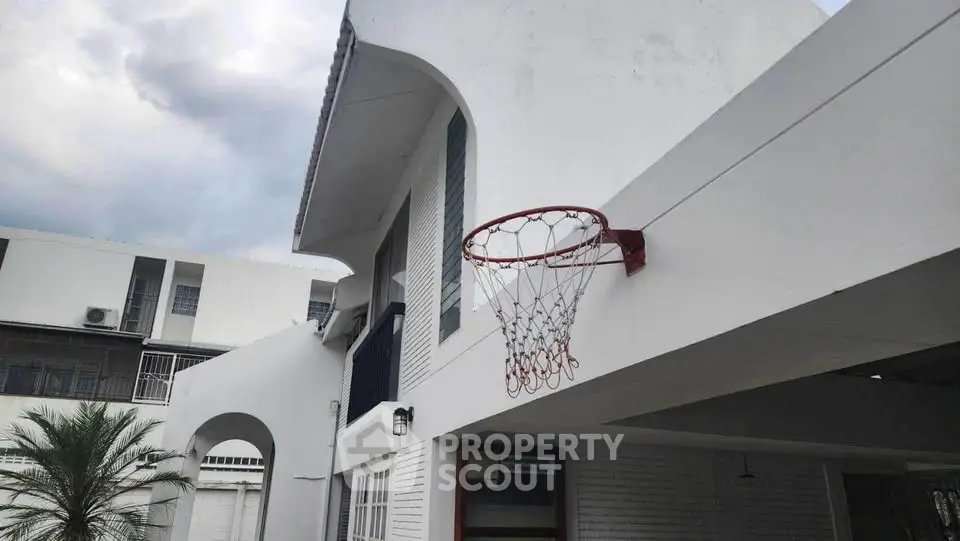 Modern white house exterior with basketball hoop and palm tree