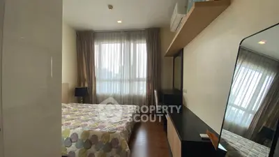 Cozy bedroom with large window and modern furnishings in a stylish apartment.