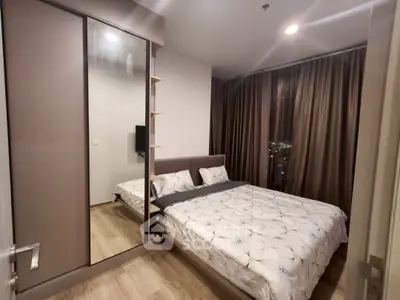 Modern bedroom with mirrored wardrobe and city view, perfect for urban living.