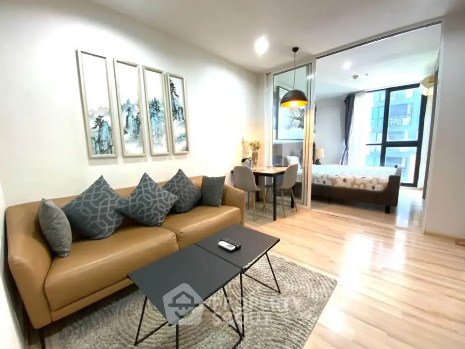 Modern living room with stylish decor and open view to bedroom, featuring cozy seating and elegant lighting.