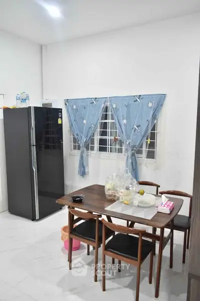 Cozy kitchen with dining table and modern fridge, perfect for family meals.