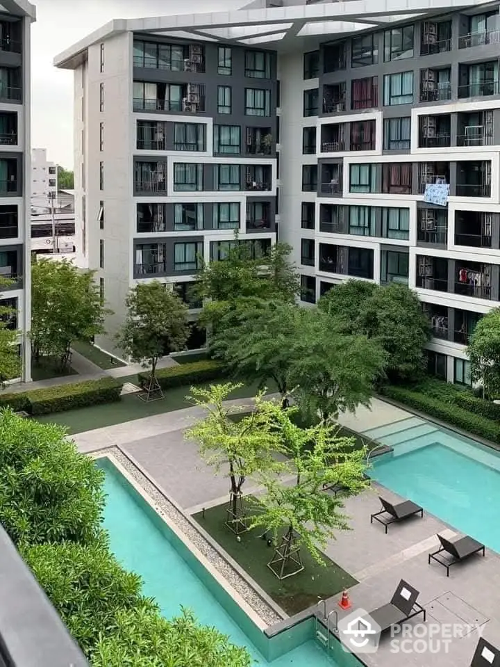 Modern apartment complex with pool and lush greenery, offering a serene urban living experience.