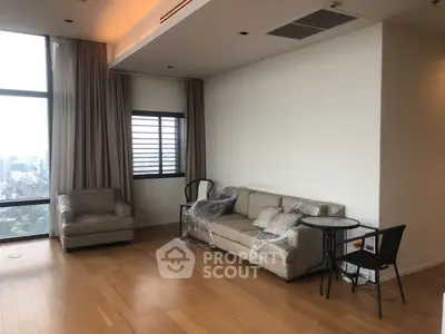 Spacious modern living room with city view, featuring elegant furniture and large windows.