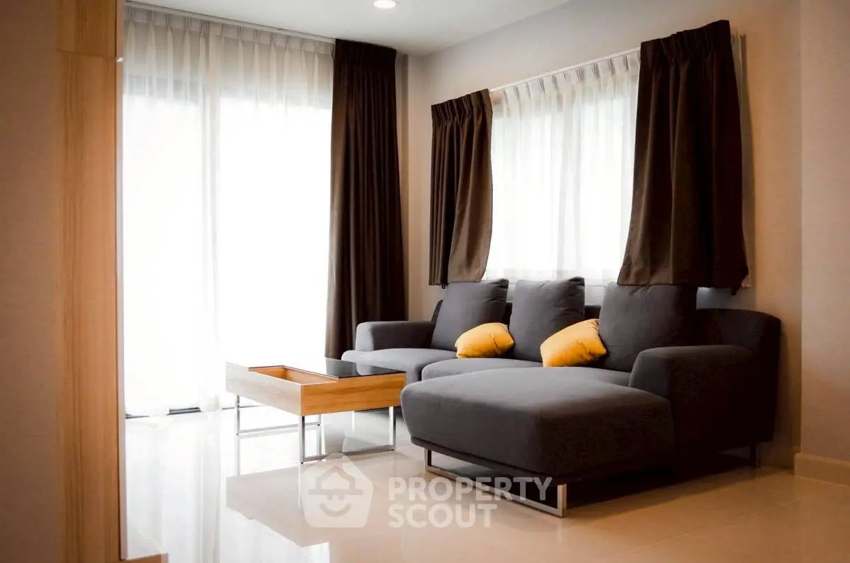 Modern living room with stylish gray sofa and natural light from large windows.