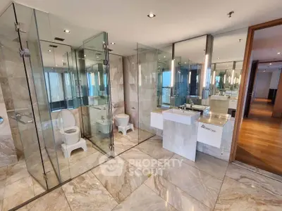 Luxurious modern bathroom with glass shower and marble flooring in high-end apartment.
