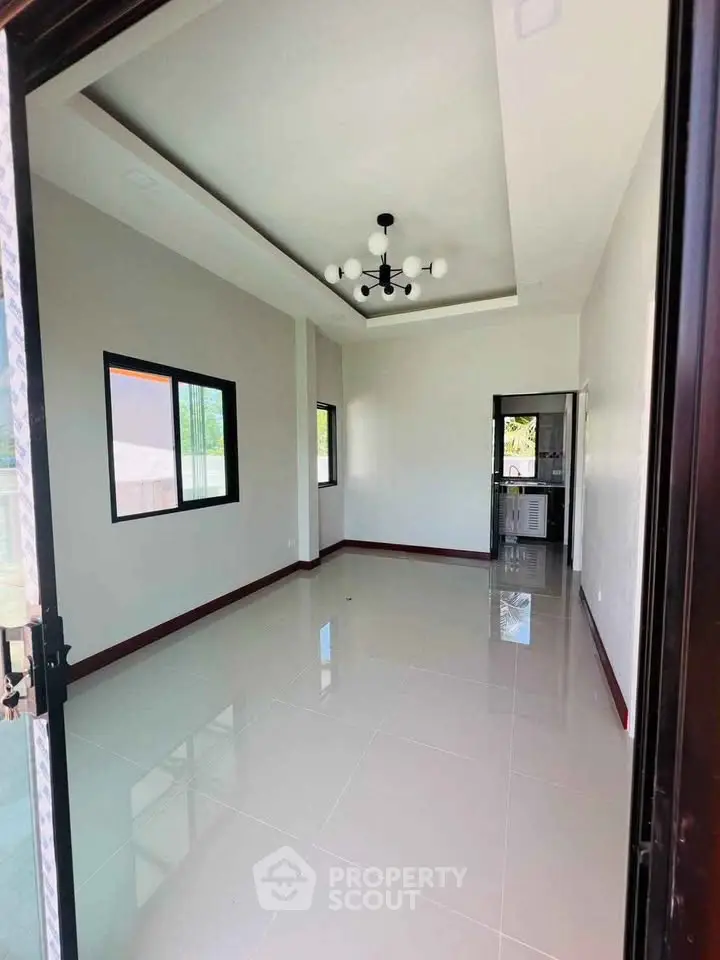 Spacious modern room with glossy tiled floors and stylish ceiling light fixture.