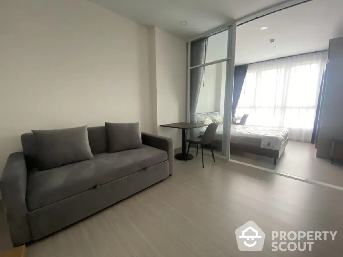 Modern studio apartment with cozy living area and bedroom separated by glass partition.