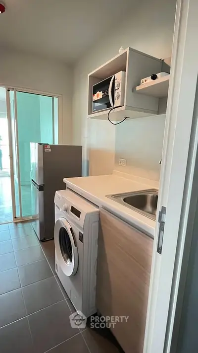 Modern kitchen with washing machine and fridge in a sleek apartment