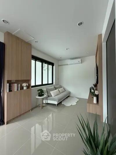 Modern living room with sleek design, featuring a cozy sofa, built-in shelves, and large window for natural light.