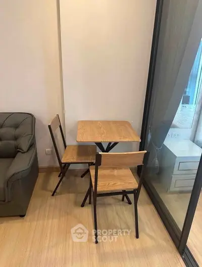 Cozy corner with a small dining set and sofa near a large window in a modern apartment.
