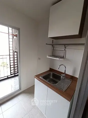 Compact kitchen with sink and balcony access in modern apartment
